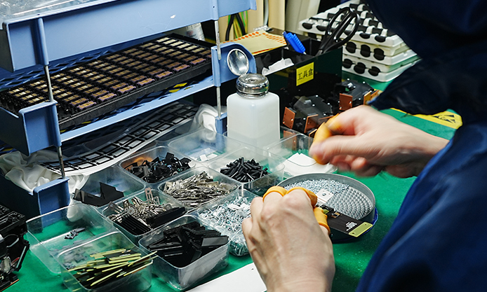 Projector Fan Noise for OEM Buyers: How to Specify and Verify a Sample 1 Worker handling an assembly beside component trays and tools at a TOUMEI workbench
